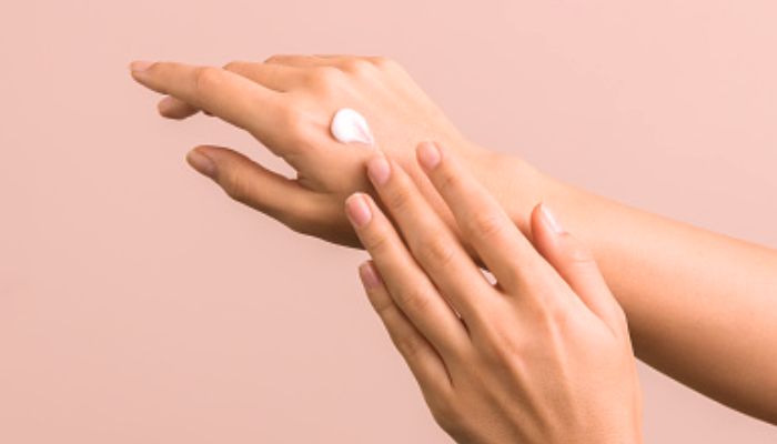  cream-on-a-womans-hand-with-pink-background