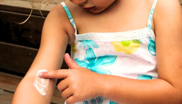  little-girl-wearing-blue-and-white-skirt-putting-cream-on-skin
