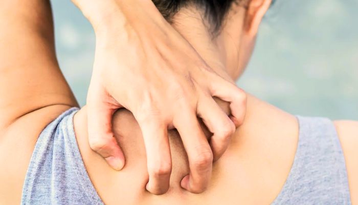 woman scratching the back of her neck in gray tanktop