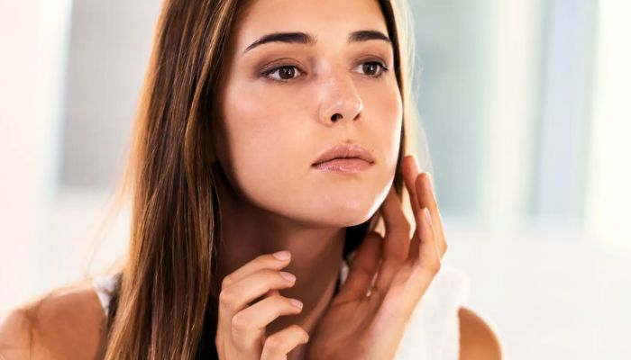 woman touching her face wearing white top