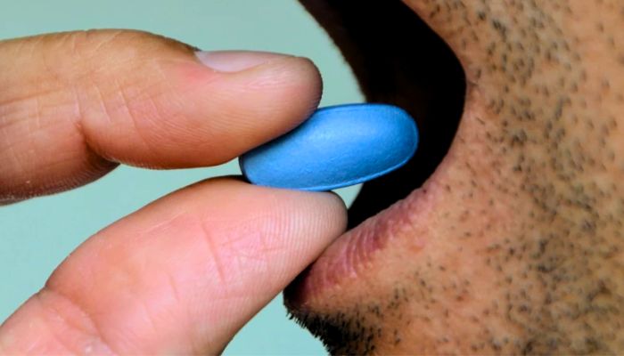 man with beard putting blue pill into this mouth